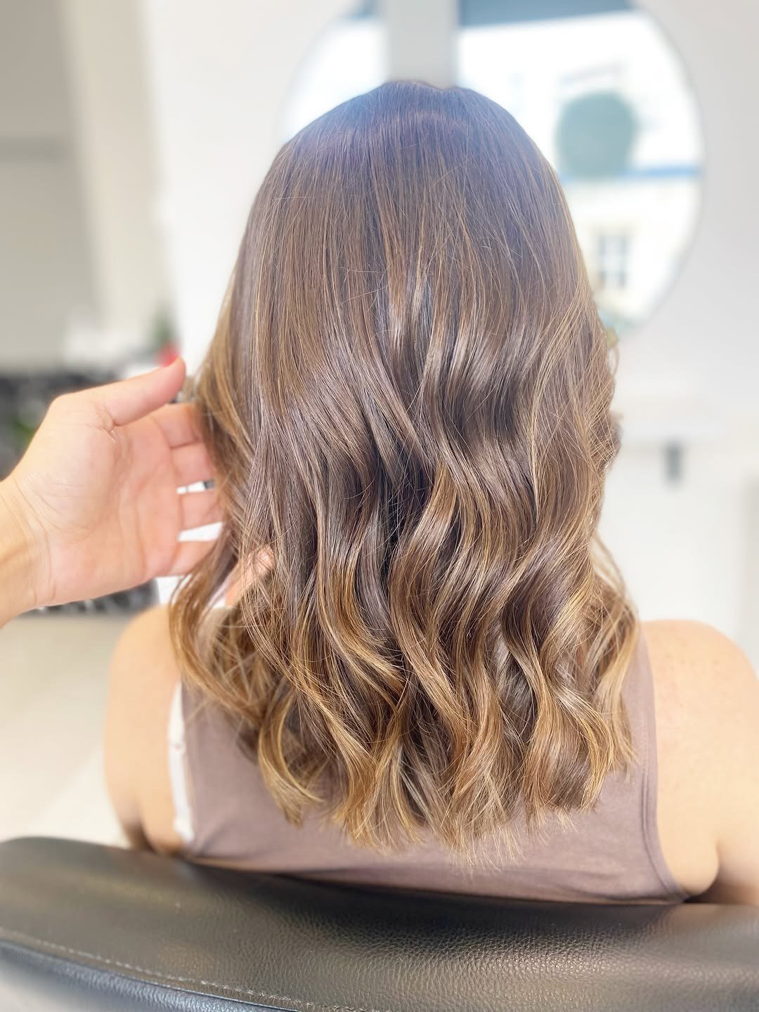 Cabelo pelos ombros em tons caramelo e beige, com ondas, visto de costas